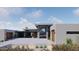 Modern home features a stone and glass entryway, a flat roof, wood garage doors, and attractive desert landscaping at 3648 N Sky Point Cir, Mesa, AZ 85207