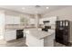 An open-concept kitchen includes white cabinets, an island, laminate floors and stainless steel appliances at 3713 S 54Th Ln, Phoenix, AZ 85043