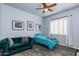 Cozy bedroom features a teal couch, twin bed, ceiling fan, and lovely window shutters at 4234 E Narrowleaf Dr, Gilbert, AZ 85298