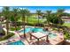 Luxurious resort-style pool with surrounding palm trees, lounging area, and a peaceful lake backdrop at 4234 E Narrowleaf Dr, Gilbert, AZ 85298