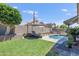 Lush backyard with well maintained lawn, private pool, rock waterfall feature, and shaded seating at 4762 E White Aster St, Phoenix, AZ 85044