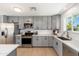 Updated kitchen boasts gray cabinets, stainless steel appliances, and bright white countertops at 6127 N 16Th Pl, Phoenix, AZ 85016