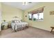 Bedroom with a large window, ceiling fan, and queen bed has neutral colored walls and carpet at 6141 S Bradshaw Way, Chandler, AZ 85249