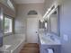 Well-lit bathroom featuring dual sinks, modern vanity, sleek fixtures, and a soaking tub at 8319 E Plata Ave, Mesa, AZ 85212