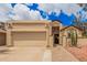 Tan stucco home with a two-car garage, gated courtyard, and desert landscaping at 10244 N 65Th Ln, Glendale, AZ 85302