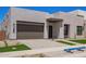 Modern home featuring desert landscaping, a gray two-car garage, and a geometric walkway at 10332 E Utah Ave, Mesa, AZ 85212
