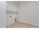 A clean, simple laundry room featuring a neutral color scheme and ample storage space above the washer-dryer hookups at 10332 E Utah Ave, Mesa, AZ 85212