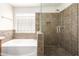 Elegant bathroom featuring a soaking tub, glass block window, and separate shower with tiled walls and flooring at 11834 N 147Th Ln, Surprise, AZ 85379