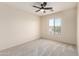 Cozy carpeted bedroom with a ceiling fan and a window overlooking the surrounding landscape at 11834 N 147Th Ln, Surprise, AZ 85379