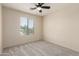 This carpeted bedroom features a ceiling fan, a window with blinds, and neutral-colored walls at 11834 N 147Th Ln, Surprise, AZ 85379