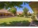 An expansive backyard with a mature tree, manicured lawn, and privacy landscaping at 129 Leisure World --, Mesa, AZ 85206