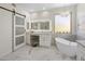 Spa-like bathroom featuring a soaking tub, vanity, illuminated mirror, chandelier, and sliding barn door at 14545 N 99Th St, Scottsdale, AZ 85260