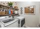 Well-organized laundry room with front-load washer and dryer, floral wallpaper, and open shelving for storage at 14545 N 99Th St, Scottsdale, AZ 85260