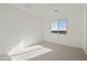 Bright bedroom featuring neutral carpet, white walls, and a window overlooking neighborhood at 19033 W Rose Ln, Waddell, AZ 85355