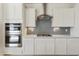 Open kitchen with stainless steel appliances, sleek cabinets, and grey subway tile backsplash at 19033 W Rose Ln, Waddell, AZ 85355
