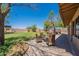 Inviting backyard patio with wicker furniture, perfect for outdoor relaxation and entertaining amidst lush greenery at 21188 N Duncan Dr, Maricopa, AZ 85138