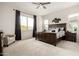 Relaxing main bedroom features a large window with black curtains, a ceiling fan, and carpet floors at 24035 N 171St Dr, Surprise, AZ 85387