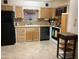 Kitchen features light wood cabinetry, tile countertops, black appliances, and tile floors at 2405 N Eastwood Way, Mesa, AZ 85215