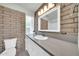 Bathroom features a brick wall accent, a grey countertop with white sink and cabinet, and a toilet at 27250 N 64Th St # 16, Scottsdale, AZ 85266