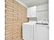 The laundry room has brick wall accents, white cabinets, and new Samsung washer and dryer at 27250 N 64Th St # 16, Scottsdale, AZ 85266