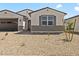Charming single-story home featuring desert landscaping, a gray front door and shuttered window at 4035 S 176Th Dr, Goodyear, AZ 85338