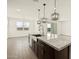 Open concept kitchen with a large center island featuring dark cabinets, a stainless sink, and modern pendant lighting at 4035 S 176Th Dr, Goodyear, AZ 85338