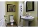 Guest bathroom with a pedestal sink, toilet, decorative mirror, and framed floral artwork at 42006 W Hillman Dr, Maricopa, AZ 85138