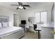 A well-lit bedroom with a silver bed frame, ceiling fan, vanity area, and neutral carpet at 42006 W Hillman Dr, Maricopa, AZ 85138