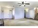 Open living room with neutral carpet, ceiling fan, access to front door and stairway at 42006 W Hillman Dr, Maricopa, AZ 85138