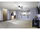 Spacious living room with neutral carpeting, a ceiling fan, and access to stairs at 42006 W Hillman Dr, Maricopa, AZ 85138