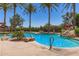 Inviting community pool area featuring a waterfall feature, lounge seating, and mature trees at 4626 E Blue Spruce Ln, Gilbert, AZ 85298