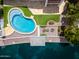 Aerial view of an impeccably maintained backyard featuring a pool, patio seating, and waterfront access on a sunny day at 5510 W Arrowhead Lakes Dr, Glendale, AZ 85308