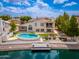 Beautiful backyard featuring a unique kidney shaped pool, dock, patio seating, and waterfront views on a sunny day at 5510 W Arrowhead Lakes Dr, Glendale, AZ 85308