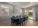 Stylish dining room featuring a dark wood table, blue chairs, and sliding glass doors to backyard at 6931 W Spur Dr, Peoria, AZ 85383
