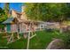 Lush backyard featuring a play structure, outdoor dining, mature tree, and covered patio, perfect for Gathering fun and entertaining at 736 S Winthrop Cir, Mesa, AZ 85204