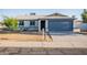 Charming single story home with a well maintained yard, desert landscaping, and a blue garage door at 8021 W Hazelwood St, Phoenix, AZ 85033