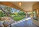 Covered back patio with lush landscaping including a grassy area, flowering plants and mature trees at 8748 W Maui Ln, Peoria, AZ 85381