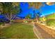 Stunning backyard with lush lawn, mature trees, and tasteful landscape lighting for serene outdoor enjoyment at 8748 W Maui Ln, Peoria, AZ 85381