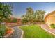 Large, manicured backyard featuring a stone pathway, waterfall, and mature trees at 8748 W Maui Ln, Peoria, AZ 85381