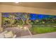 Cozy covered patio offers a serene view of the lush backyard and ambient landscape lighting at 8748 W Maui Ln, Peoria, AZ 85381