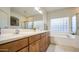 Bright bathroom has dual sinks, soaking tub, glass-enclosed shower and tile floors at 8748 W Maui Ln, Peoria, AZ 85381