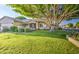 Beautiful home showcasing lush green lawn, mature tree, and covered front entry at 8748 W Maui Ln, Peoria, AZ 85381