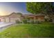 Well-manicured front yard with lush green grass, mature trees, and desert landscaping at 8748 W Maui Ln, Peoria, AZ 85381