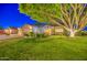Beautiful home exterior boasts green lawn, mature tree and landscaping, and well-lit entry at 8748 W Maui Ln, Peoria, AZ 85381