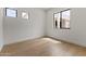 Bright, minimalist bedroom with hardwood floors, a large window, and white walls, offering a serene space at 9611 E Clinton St, Scottsdale, AZ 85260