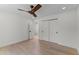A well-lit room with a wooden ceiling fan, light hardwood floors, and white walls at 9611 E Clinton St, Scottsdale, AZ 85260