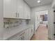 Well-lit kitchen featuring white cabinetry, marble countertops, and modern hardware, complete with marble backsplash accents at 9611 E Clinton St, Scottsdale, AZ 85260