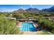 Aerial view of community pool with lounging area, set against a backdrop of mountains and desert landscape at 10179 E Camelot Ct, Scottsdale, AZ 85255