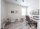 Bright bedroom features wood-look flooring, white walls, and a cozy workspace with a modern desk and office chair at 10849 S 175Th Dr, Goodyear, AZ 85338