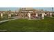 A bright, sunny day view of the neighborhood playground, with covered picnic tables and play equipment on artificial turf at 10849 S 175Th Dr, Goodyear, AZ 85338